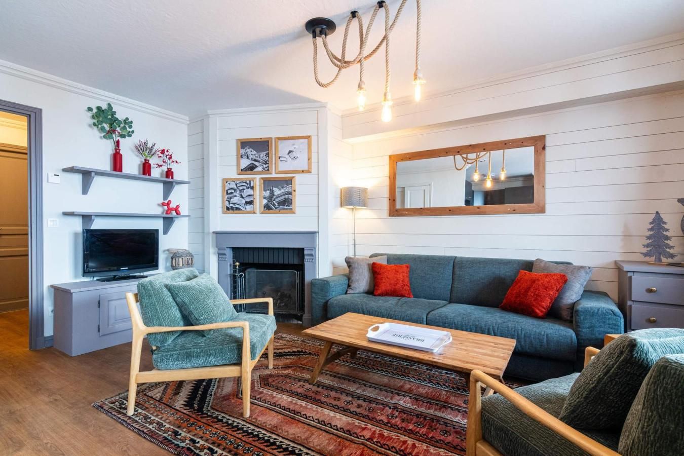 A living room with a sofa, chairs, a TV, a fireplace, and a mirror.