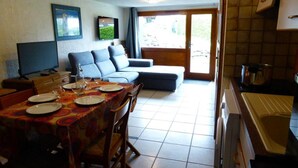 Un comedor con una mesa dispuesta para cuatro personas, un sofá y una televisión.