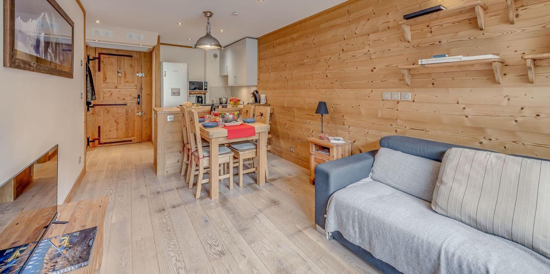 A cozy cabin interior with a dining area, a sofa, and wooden walls.