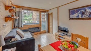 A cozy living room with a sofa, TV, and dining table. - 1st floor, tv, ski locker, 50m², Tignes (Tignes)