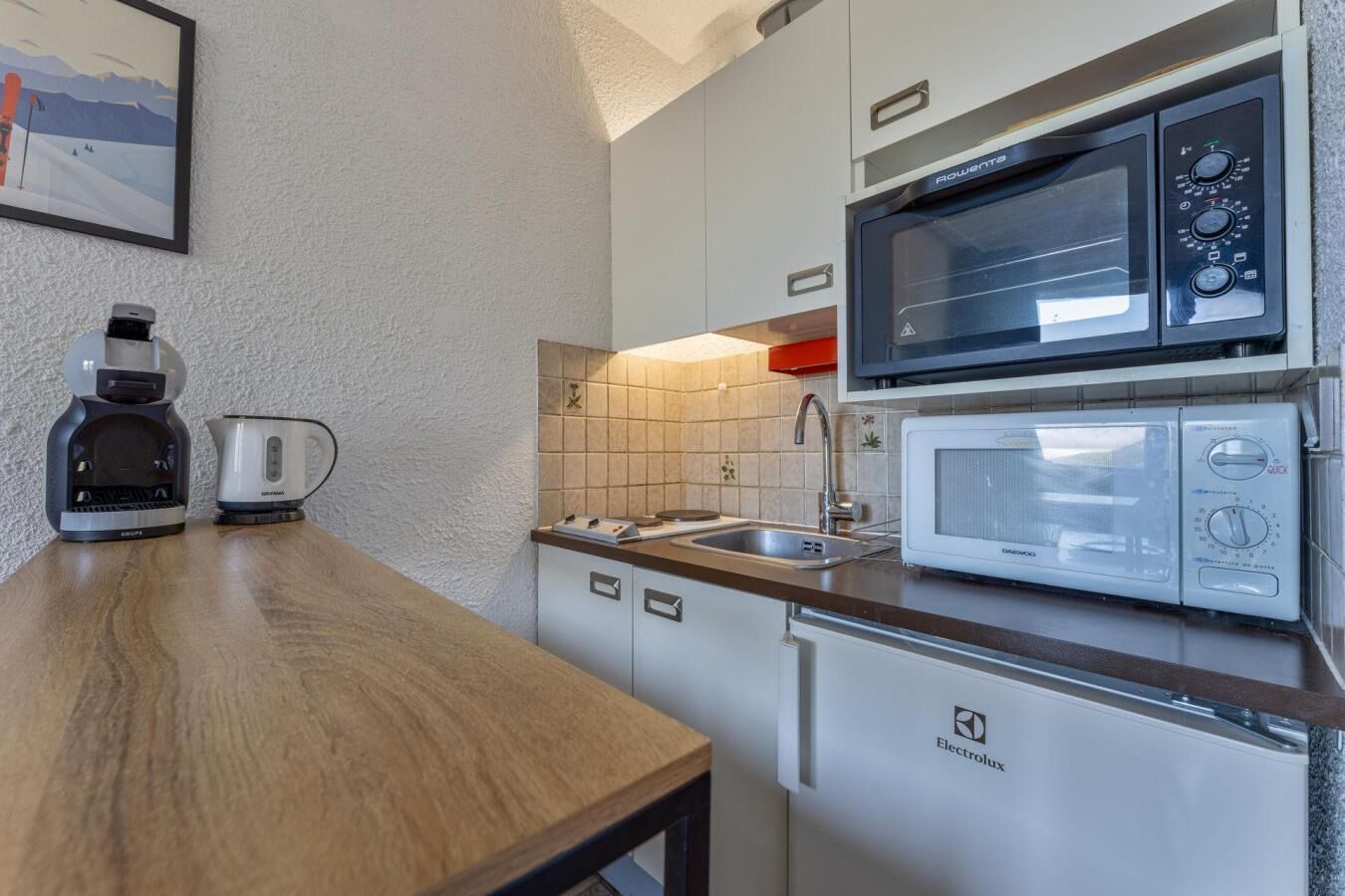 Una cocina compacta equipada con microondas, hervidor y cafetera.