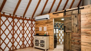 Ein rustikaler Innenraum mit einem Holzschrank, einer Schiebetür im Scheunenstil und einer weißen Klimaanlage, die an der Decke angebracht ist.