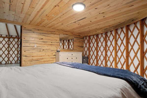 Un dormitorio con paneles de madera, una cama, un tocador y un espejo.