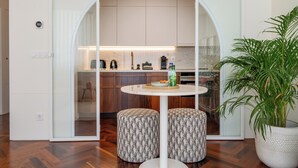 Una cocina moderna con una mesa redonda, otomanas, una planta en maceta y armarios de madera.