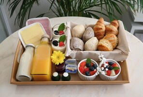 A tray with breakfast items including croissants, pastries, fresh berries, and dairy products.
