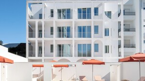 Un edificio moderno con piscina, zona de estar al aire libre y cielo azul despejado.