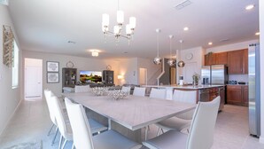 Une cuisine moderne dotée d’un grand îlot central, de meubles blancs et d’appareils électroménagers en acier inoxydable.