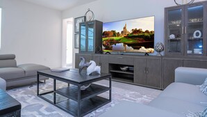 Un salon moderne doté d’un téléviseur à écran plat, de canapés gris, d’une table basse et d’un meuble avec des portes en verre.