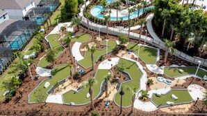 A golf course with multiple putting greens, a central water feature, and surrounding palm trees. - DLuxx Beautiful Decor House fun Waterpark 1171 (Davenport)