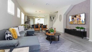 A modern living room with a grey sofa, a coffee table, and a TV mounted on the wall. - DLuxx Beautiful Decor House fun Waterpark 1171 (Davenport)