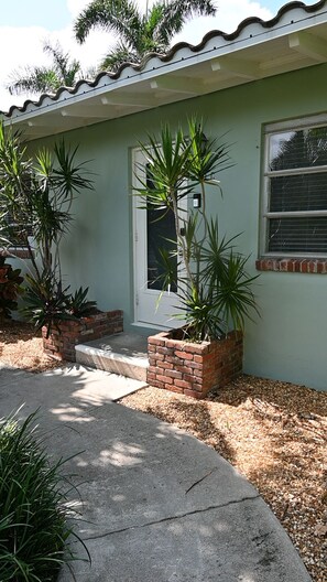 A house with a front porch, a door, and two potted plants.