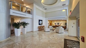 A spacious lobby with a high ceiling, marble flooring, and a seating area with sofas and chairs.