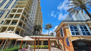 A high-rise hotel with multiple balconies, outdoor seating areas, and palm trees.