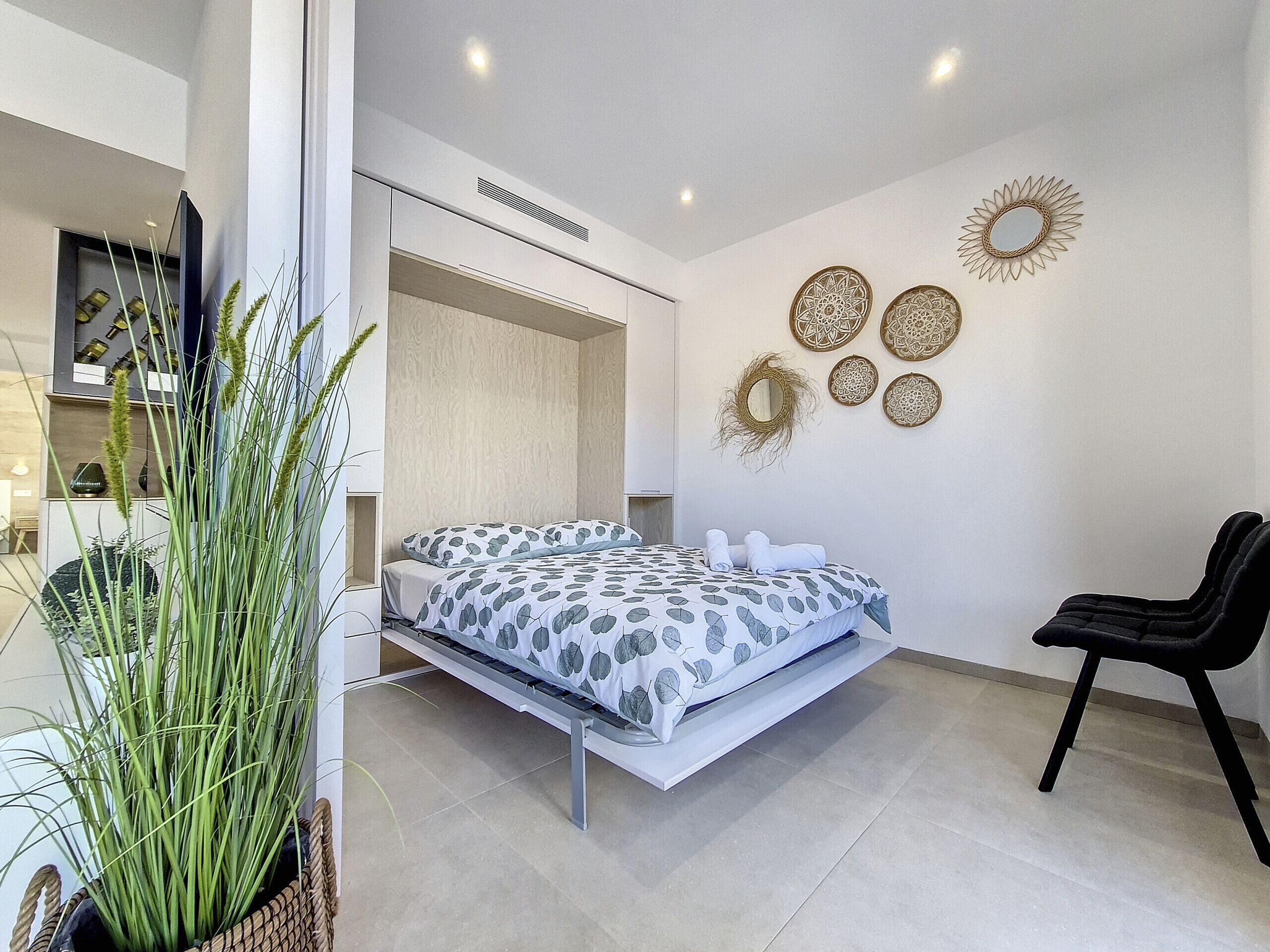 A modern bedroom with a bed, a chair, and decorative wall art.