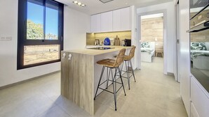A modern kitchen with a wooden island, bar stools, and a view through the window. - Penthouse apartment with pool, parking and Wi-Fi (San Pedro del Pinatar)