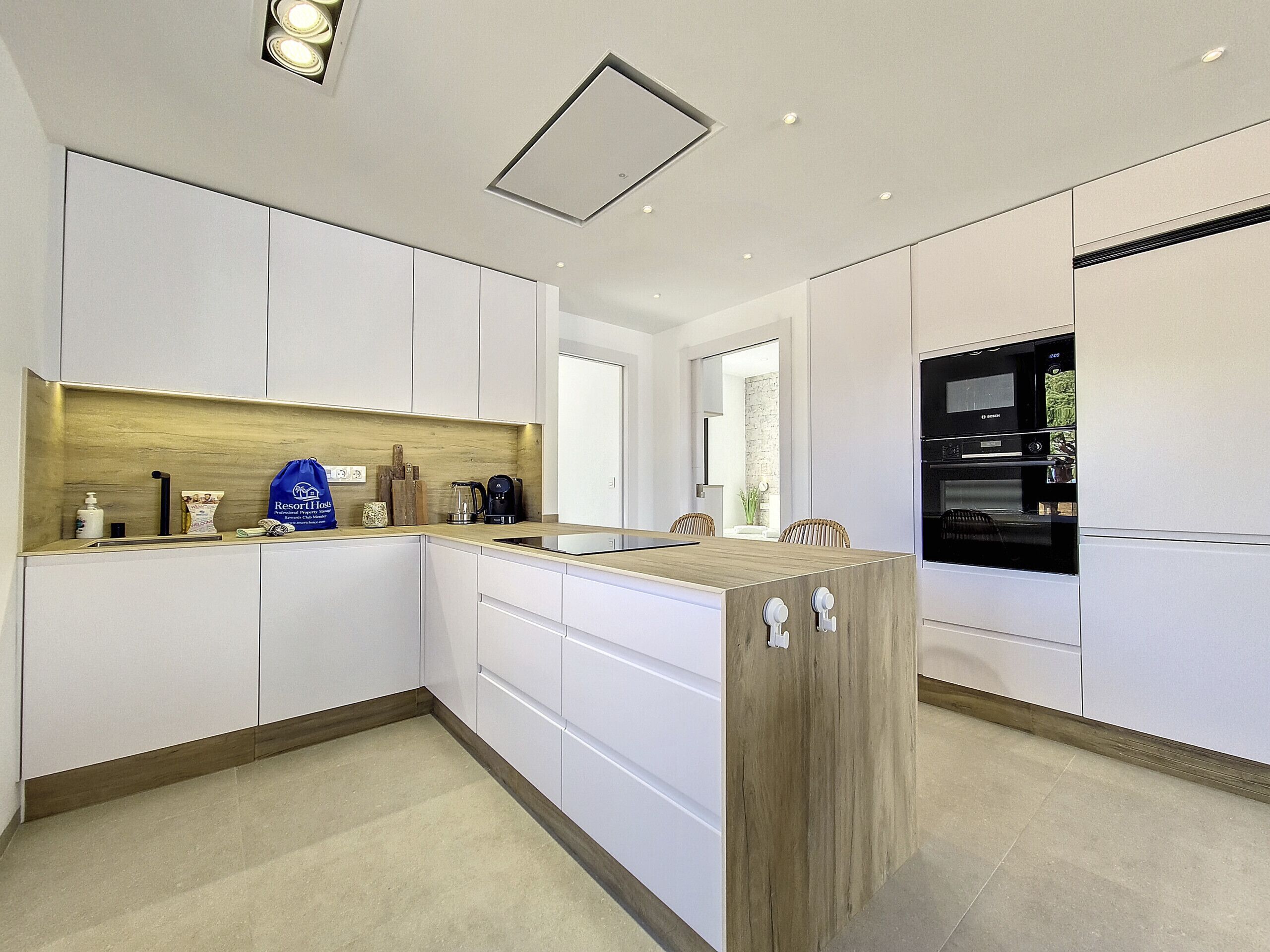 A modern kitchen with white cabinetry, a wooden countertop, and a built-in oven.