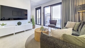 A modern living room with a flat-screen TV, a sofa, a coffee table, and a balcony with a view. - Penthouse apartment with pool, parking and Wi-Fi (San Pedro del Pinatar)
