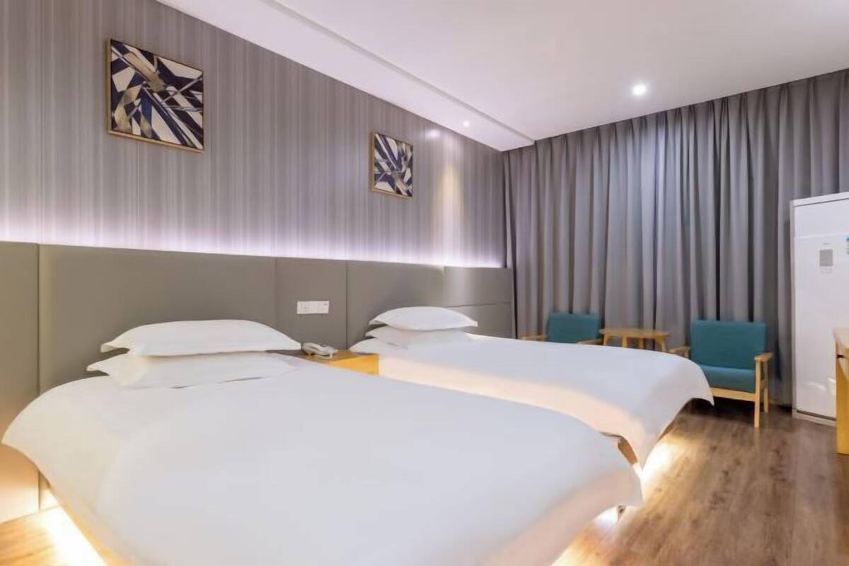 A hotel room with two beds, a desk, a chair, and a wardrobe.