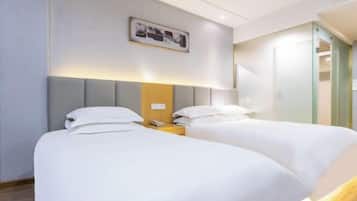 Una habitación de hotel con dos camas, una mesita de noche con lámpara y un cuadro en la pared.