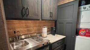 Eine kleine Küche mit dunklen Holzschränken, Edelstahlgeräten und einer Arbeitsplatte.