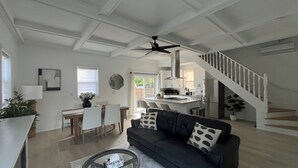 A spacious living area with a black leather sofa, a dining table with chairs, a kitchen area, and a staircase. - Water view - Perfect location - Modern cottage in Niagara region  (Niagara-on-the-Lake)