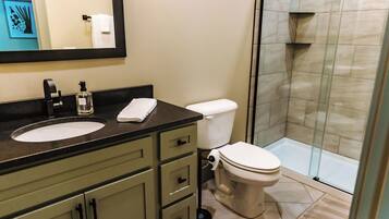 A bathroom with a sink, toilet, and glass-enclosed shower.