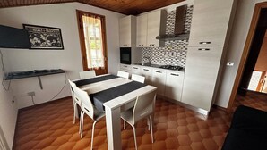 A modern kitchen with white cabinets, a tiled backsplash, and a dining area with a table and chairs.