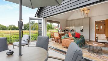 A modern open-plan living area with a dining table, chairs, and a sofa with cushions.
