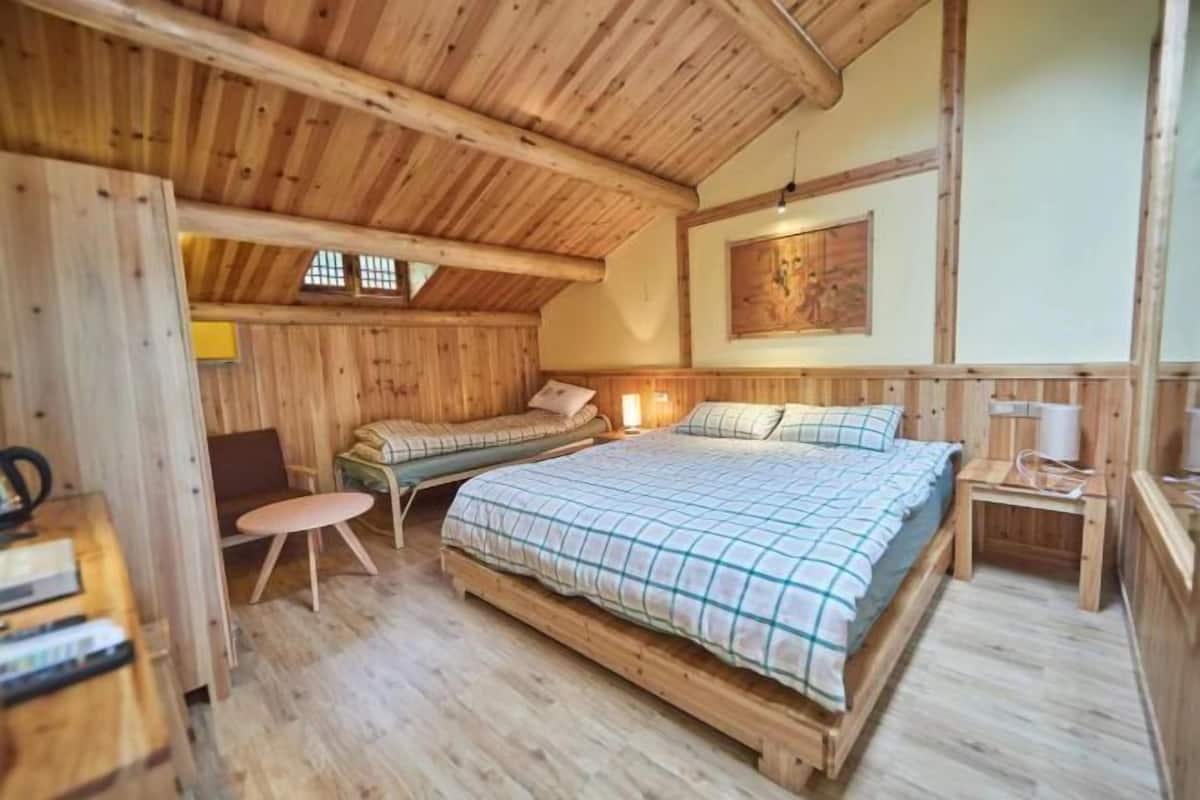 A wooden cabin-style room with a bed, a small table, and a bench.