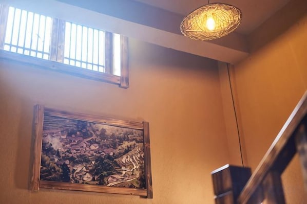 Una escalera con barandilla de madera, una lámpara de pared y una obra de arte enmarcada.