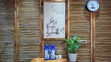 A wooden wall with a framed artwork, a clock, and a small table with bottles and a plant.