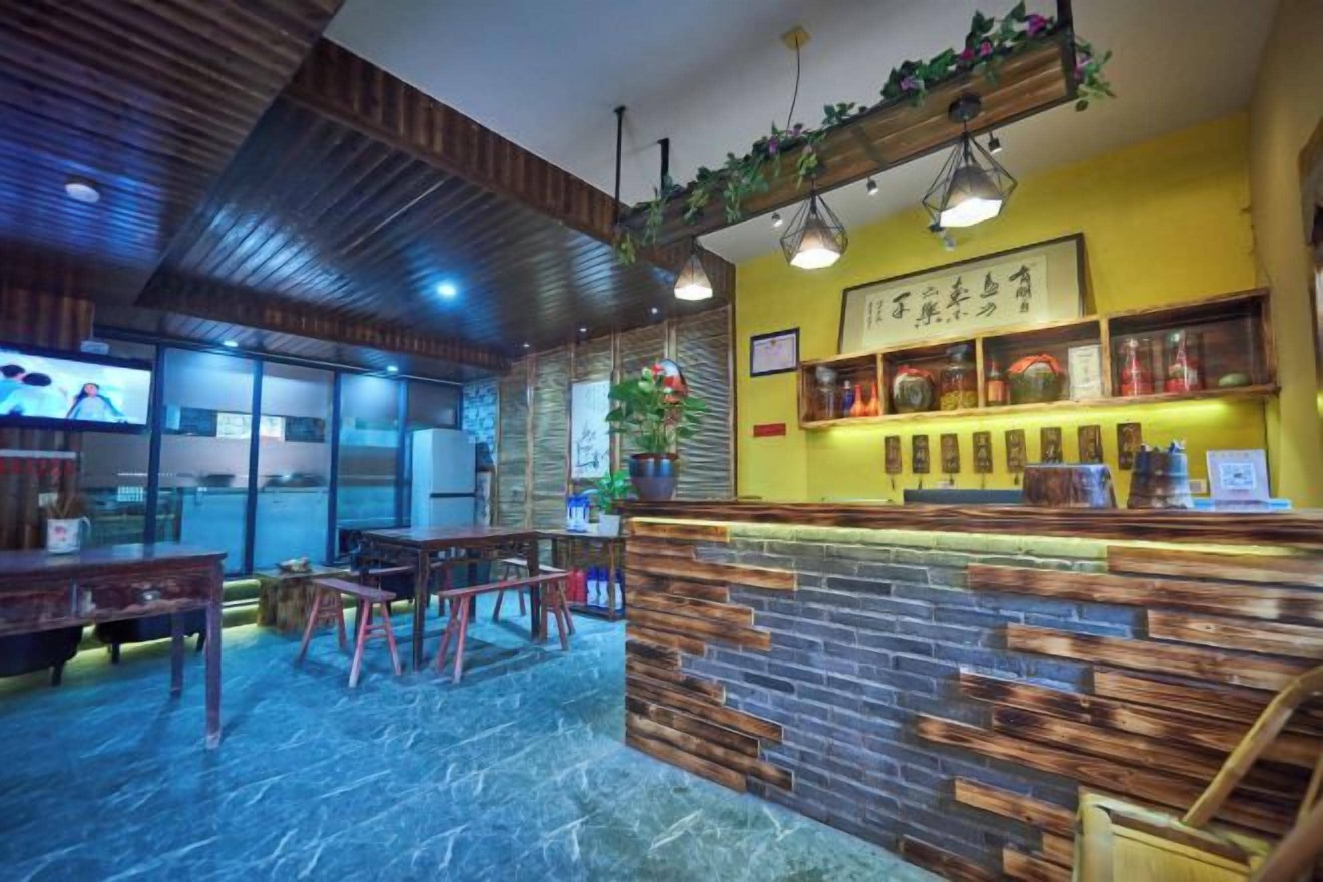 A restaurant interior with a bar area, wooden furniture, and a yellow accent wall.