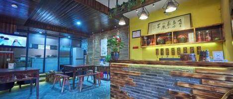 A restaurant interior with a bar area, wooden furniture, and a yellow accent wall.