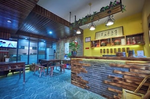 Interior de un restaurante con barra, mobiliario de madera y una pared de acento amarilla.