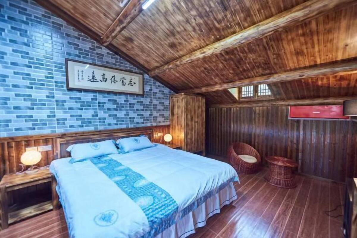 A room with a bed, wooden walls, a brick wall, and a mounted TV.