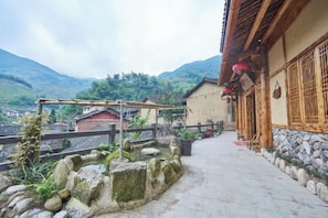 Un edificio tradicional con un sendero de piedra que lleva a una estructura de madera, rodeado de montañas.