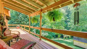 A wooden deck with a view of a forest, a hanging plant, and a bird feeder. - Private, Secluded Cabin on 30 Acres in Cosby! (Cosby)