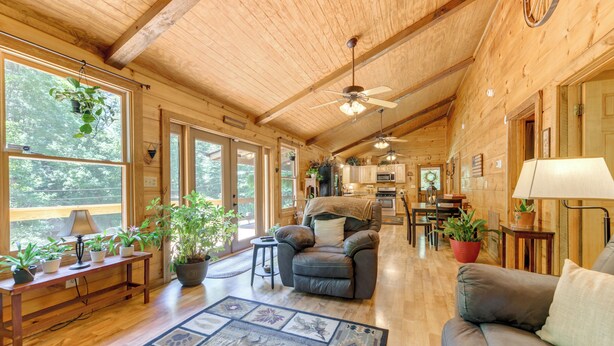 A spacious wooden cabin interior with a dining area, kitchen, and seating area. - Private, Secluded Cabin on 30 Acres in Cosby! (Cosby)