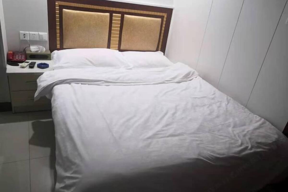 A hotel room with a bed, a nightstand, and a wall socket.