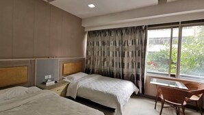 Habitación de hotel con dos camas, un escritorio y una silla.