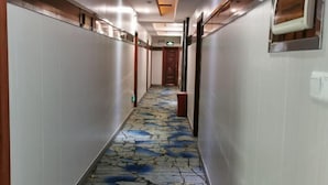 Un pasillo con piso estampado, paredes blancas y una puerta de madera al final.