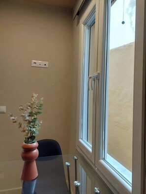 A cozy space with a potted plant on a reflective table, complemented by a comfortable chair and a window with a single handle.