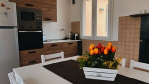 Una cocina moderna con armarios de madera, horno empotrado y comedor con mesa dispuesta para dos.