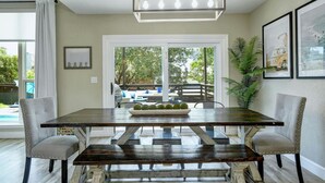 A dining area with a dark wooden table, cushioned chairs, and a pendant light fixture.