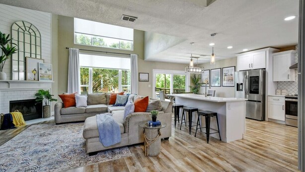 A spacious living room with a fireplace, a large sofa, and a kitchen area with modern appliances.