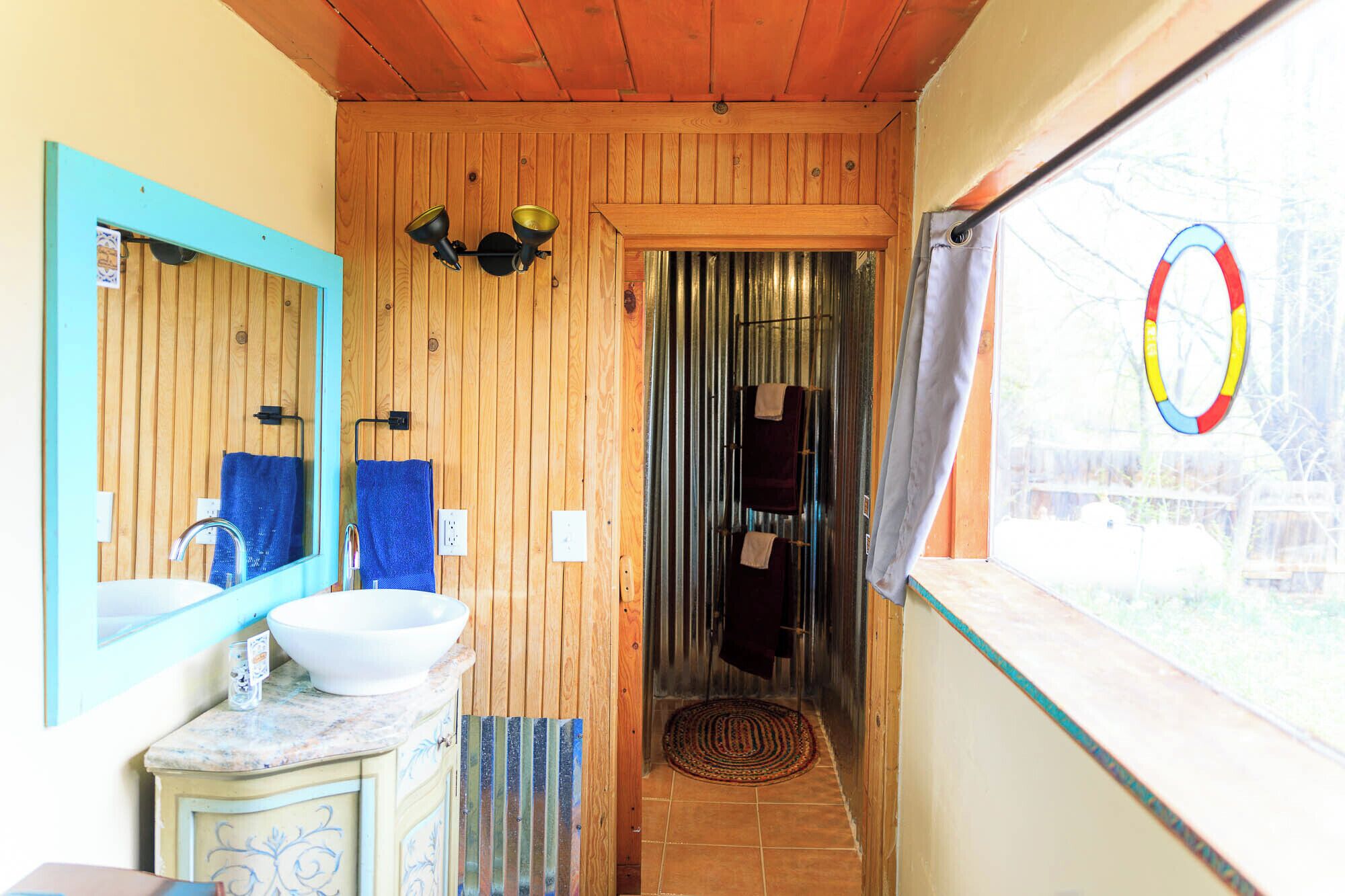 Een badkamer met een houten plafond, een wastafel met een marmeren aanrechtblad en een spiegel.