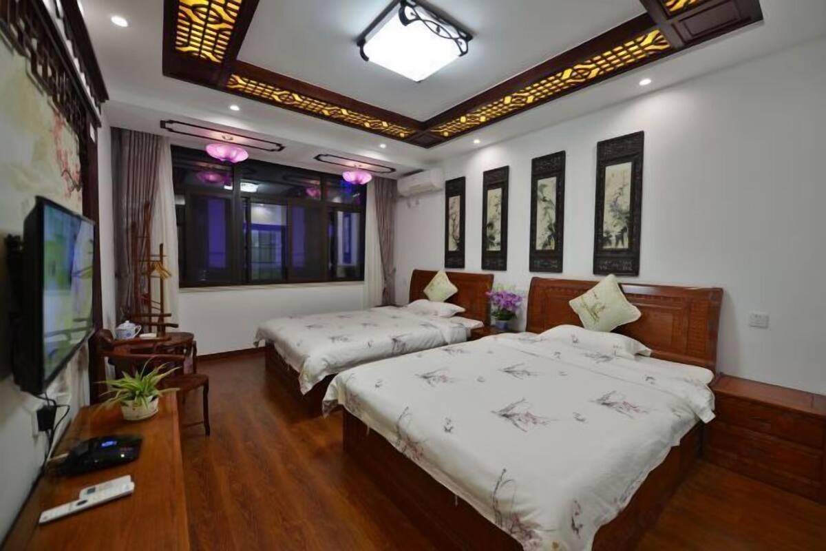 A hotel room with two beds, a desk, a TV, and artwork on the walls.