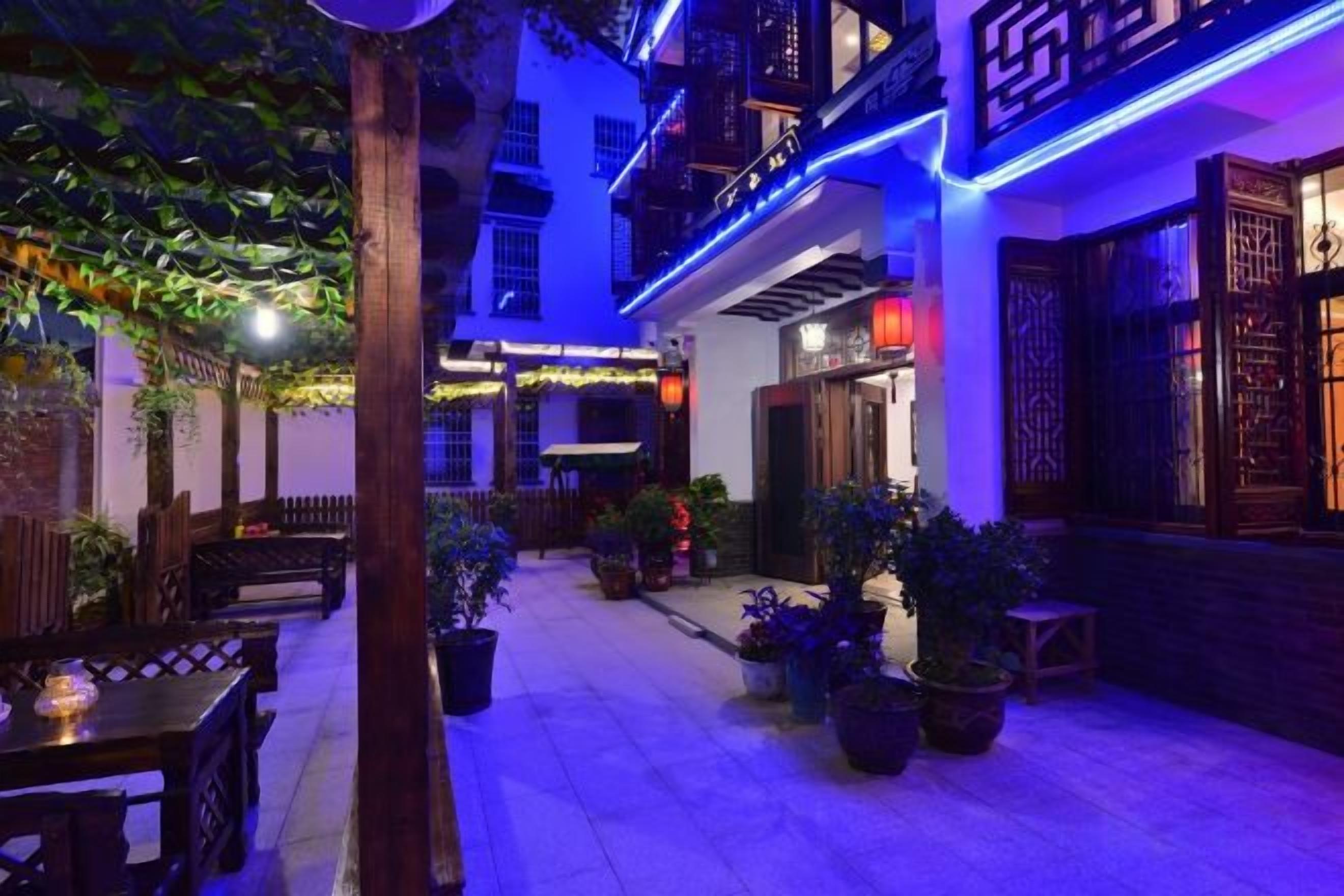 A courtyard with potted plants, wooden furniture, and traditional architectural elements.