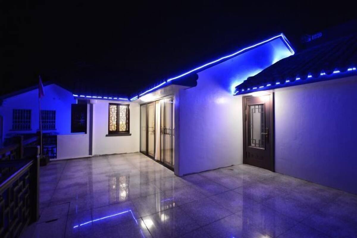 A building with a tiled patio and blue LED lighting along the roofline.