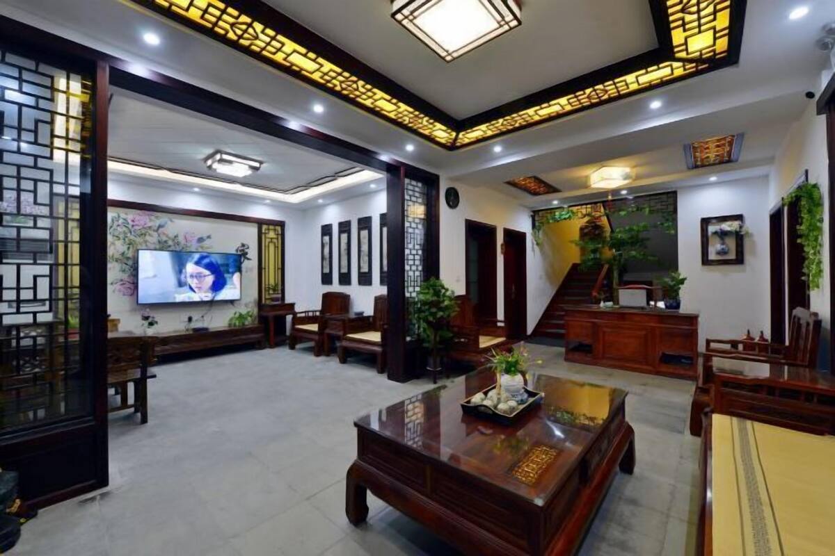 A spacious living area with a large TV, wooden furniture, and a staircase leading to another level.